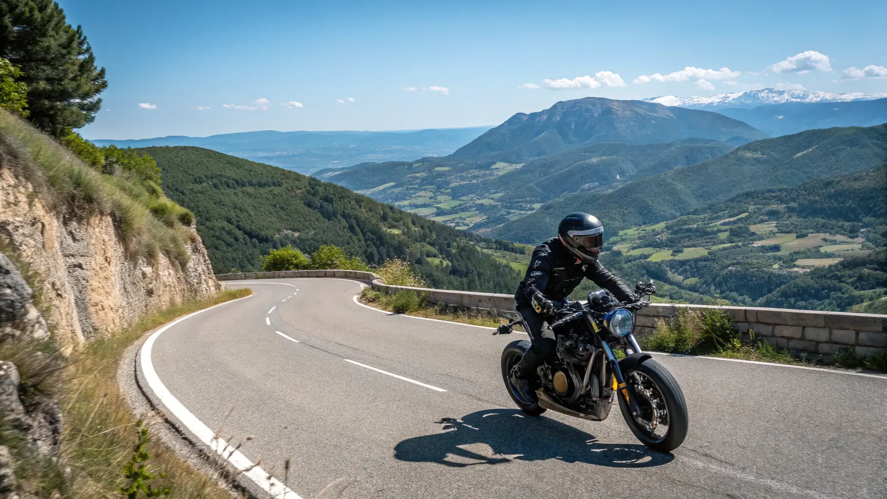 A motorcyclist wearing full safety gear (helmet, jacket, gloves) riding on a scenic road.