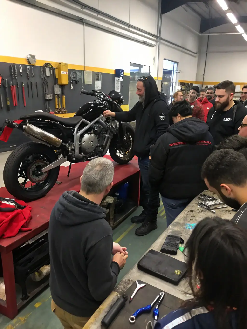 Volunteers assisting with motorcycle maintenance at a ROAD INDEPENDENT workshop, emphasizing the community support and skill-sharing aspect.